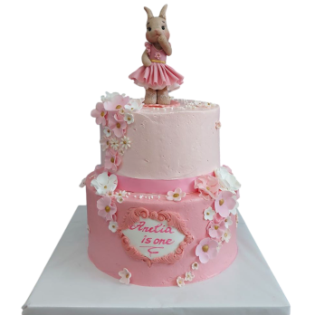 Two-tier pink cake with a ballerina bunny and a cascade of flowers - a first birthday cake.